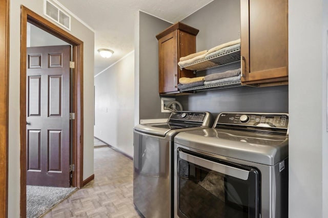 washroom with light parquet floors, separate washer and dryer, and cabinets