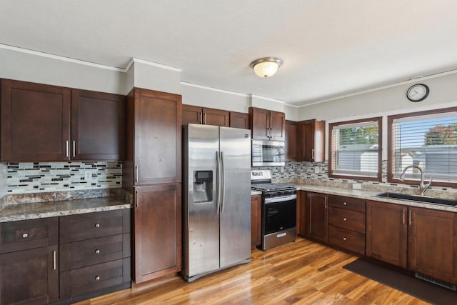 kitchen featuring ornamental molding, sink, appliances with stainless steel finishes, light wood-type flooring, and decorative backsplash