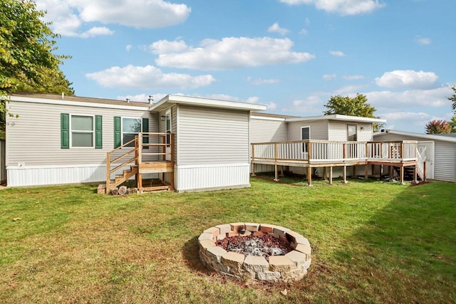 rear view of house featuring an outdoor fire pit, a yard, and a deck