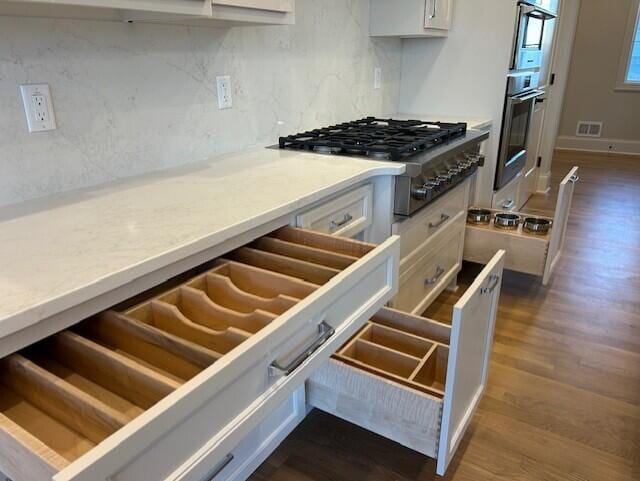 kitchen featuring tasteful backsplash, hardwood / wood-style floors, white cabinets, and appliances with stainless steel finishes