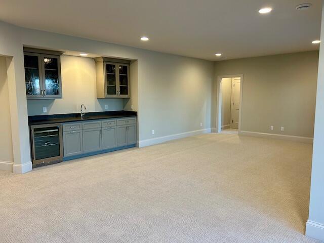 interior space with light colored carpet, sink, and wine cooler