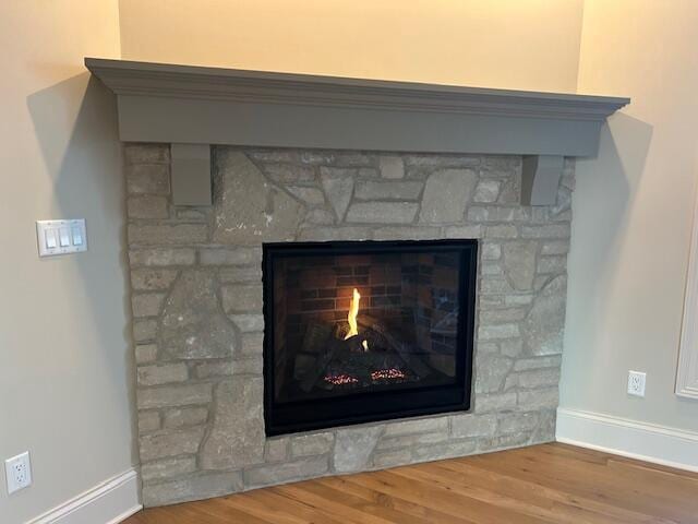 room details with hardwood / wood-style floors and a stone fireplace