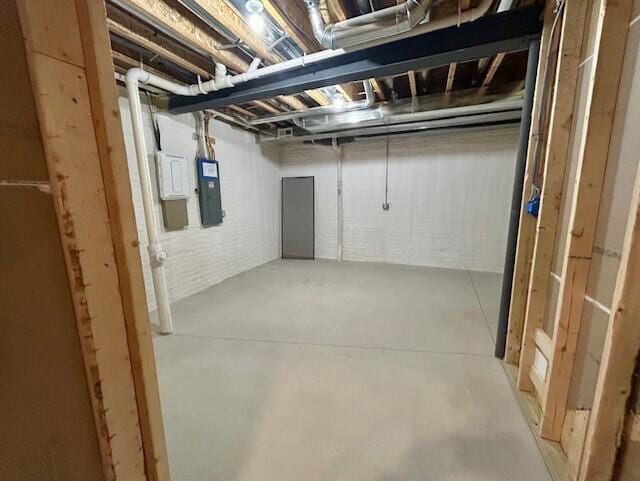 basement with electric panel and brick wall