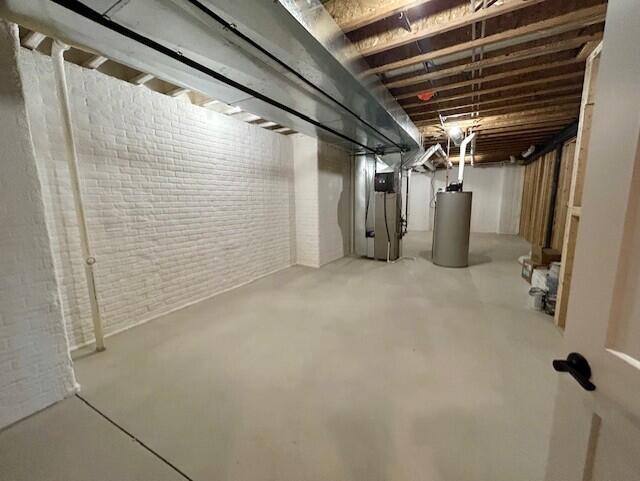 basement featuring heating unit, brick wall, and gas water heater