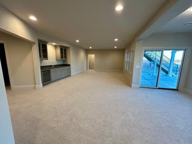 unfurnished living room with light colored carpet and sink