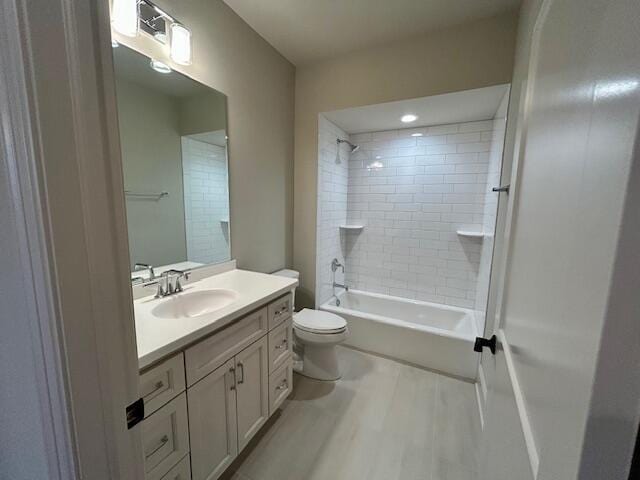 full bathroom with vanity, toilet, wood-type flooring, and tiled shower / bath