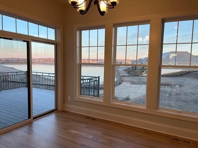 entryway with hardwood / wood-style floors, a water view, and a notable chandelier