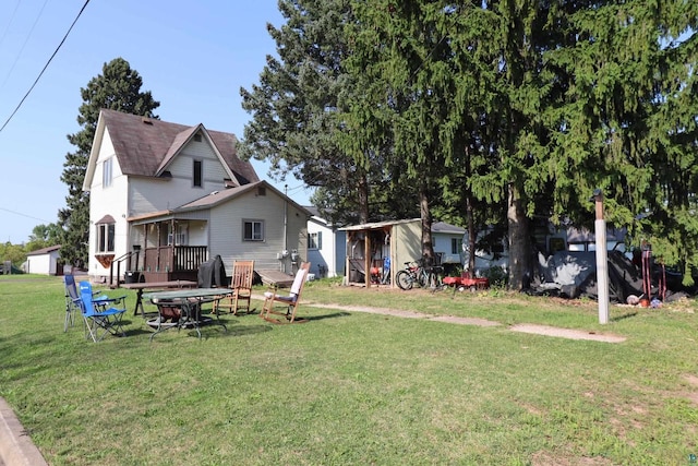 back of property featuring an outdoor fire pit, a yard, and a carport