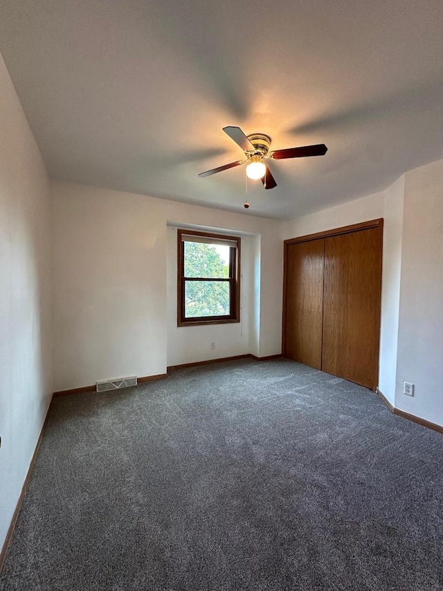 unfurnished bedroom featuring a closet, dark carpet, and ceiling fan