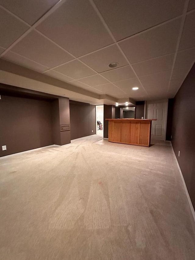 basement featuring a paneled ceiling and carpet floors