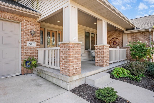 view of exterior entry featuring covered porch and a garage