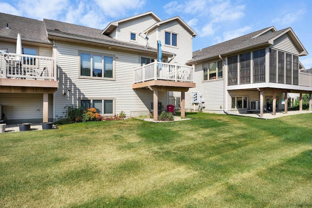 back of house with a deck, a lawn, and a sunroom