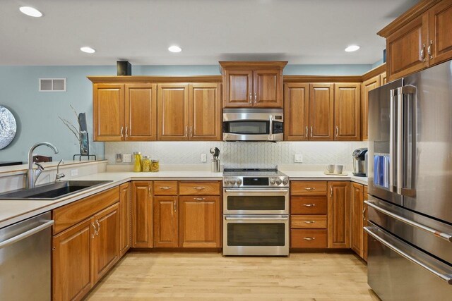 kitchen featuring sink, appliances with stainless steel finishes, light hardwood / wood-style floors, and tasteful backsplash