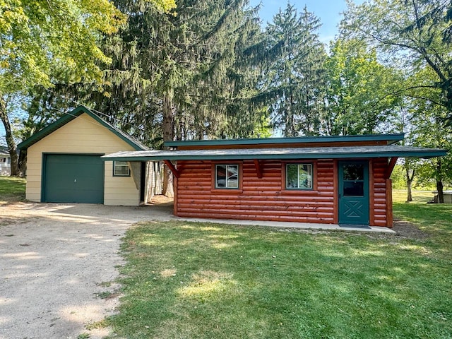 log cabin with a garage, a carport, a front lawn, and an outbuilding