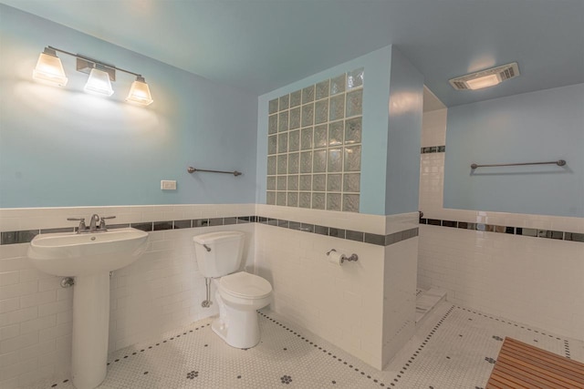 bathroom with tile patterned floors, toilet, tile walls, and sink