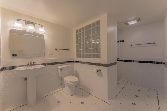 bathroom featuring tile patterned floors, tile walls, and toilet