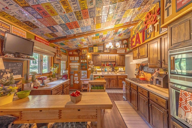 kitchen with appliances with stainless steel finishes, hardwood / wood-style flooring, vaulted ceiling, and butcher block counters