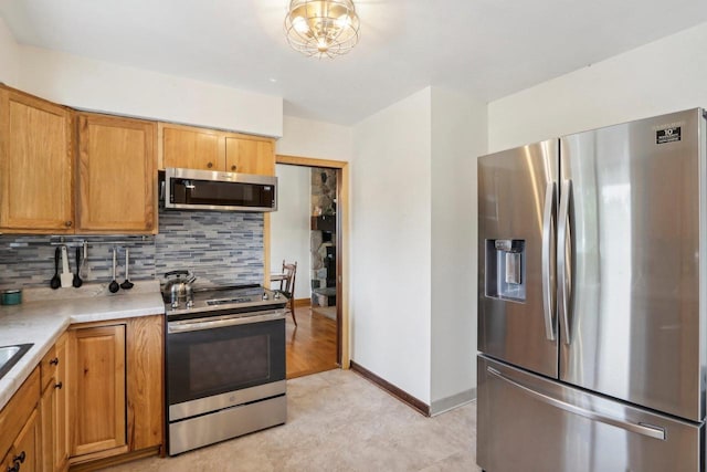 kitchen with light wood-type flooring, backsplash, an inviting chandelier, and stainless steel appliances