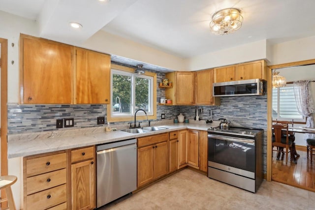 kitchen with appliances with stainless steel finishes, decorative backsplash, light hardwood / wood-style flooring, sink, and a notable chandelier