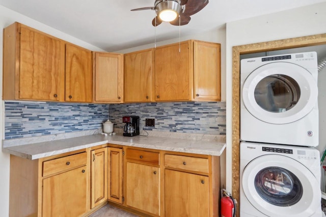 washroom with ceiling fan and stacked washer / dryer