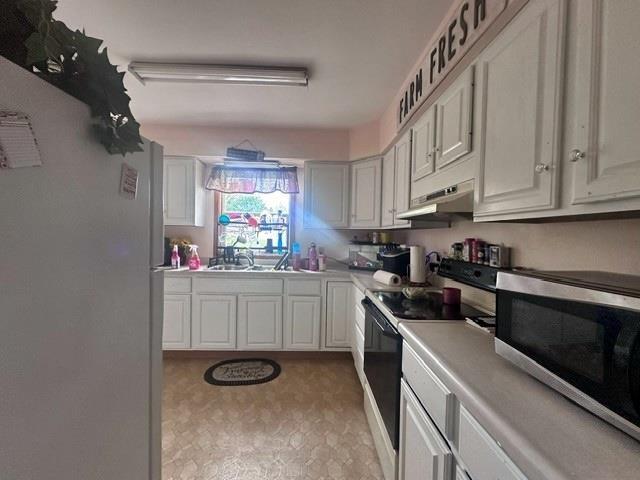 kitchen featuring white fridge, white cabinetry, range with electric cooktop, and sink