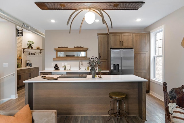 kitchen with sink, hardwood / wood-style floors, stainless steel fridge with ice dispenser, and a kitchen island