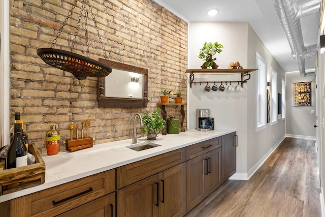 bar featuring hardwood / wood-style floors, sink, and brick wall