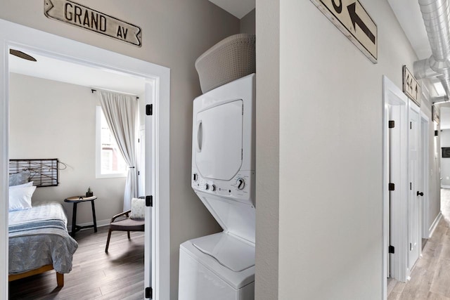 laundry area with stacked washer and clothes dryer and light hardwood / wood-style flooring