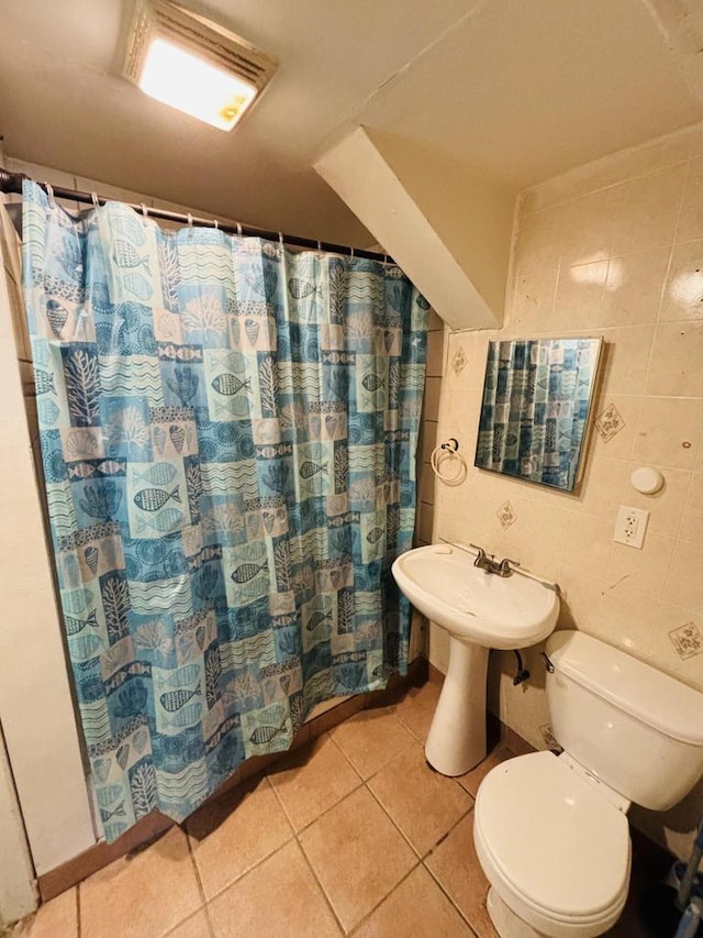 bathroom with toilet, tile patterned floors, tile walls, and walk in shower