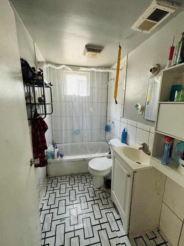 full bathroom featuring vanity, tiled shower / bath combo, tile walls, and toilet