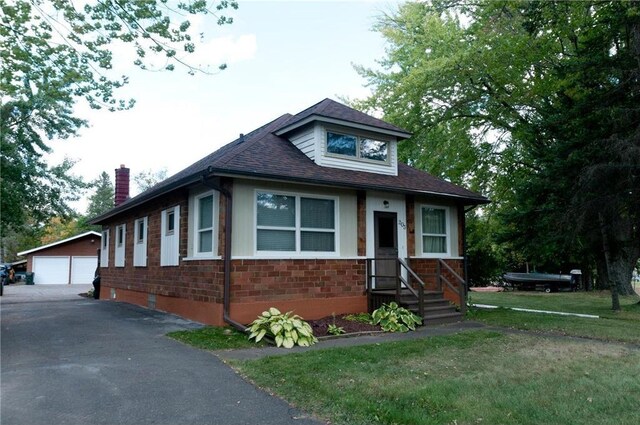 view of front of house featuring a front yard, a garage, and an outdoor structure