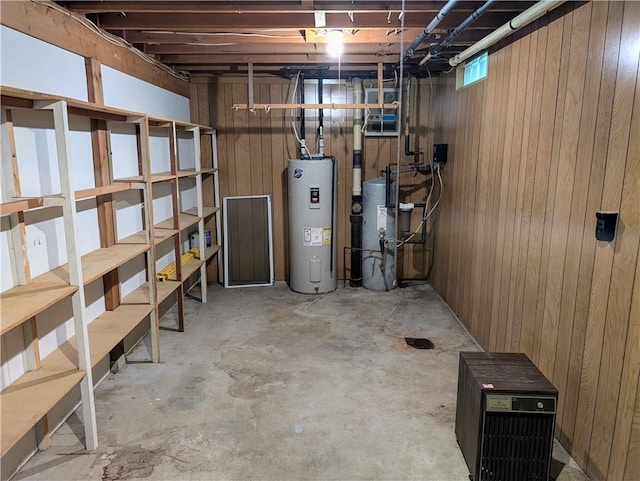 basement with gas water heater, water heater, and wood walls