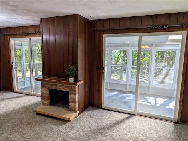 unfurnished living room featuring wooden walls, carpet floors, and a fireplace