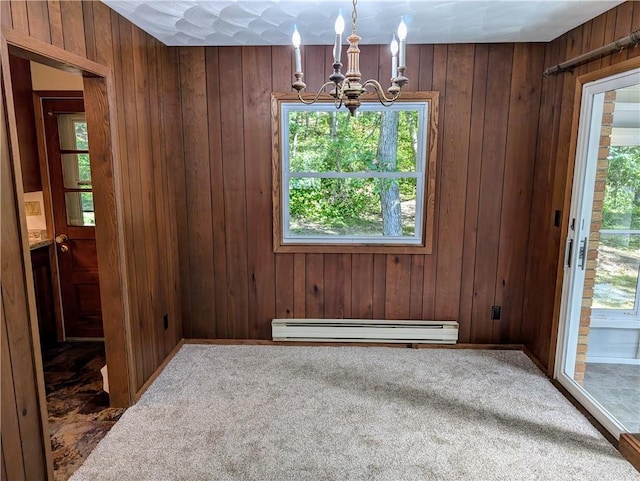 unfurnished dining area with baseboard heating, carpet flooring, wooden walls, and an inviting chandelier