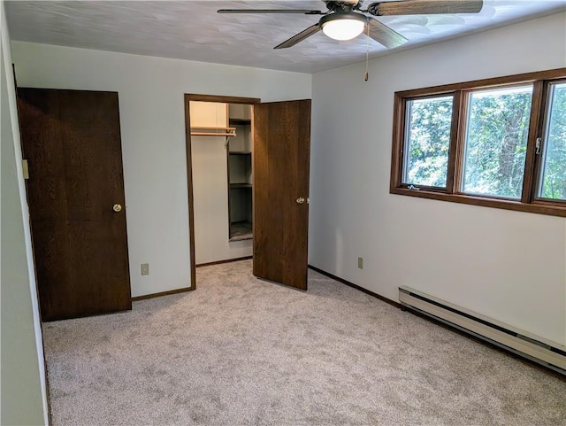 unfurnished bedroom with ceiling fan, a closet, a spacious closet, light colored carpet, and a baseboard radiator