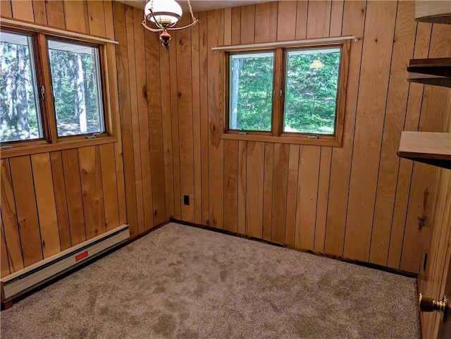 empty room with light carpet, a baseboard radiator, wooden walls, and a wealth of natural light