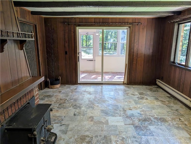 interior space with wooden walls, beam ceiling, and a wood stove