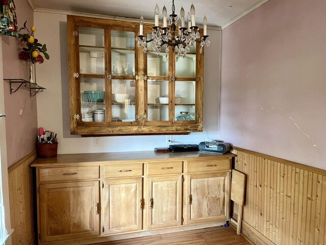 interior space with crown molding, wooden walls, an inviting chandelier, and hardwood / wood-style flooring