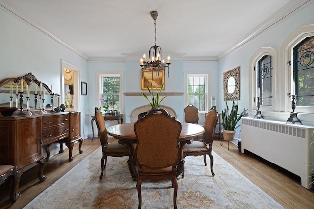 dining area featuring ornamental molding, light hardwood / wood-style flooring, a chandelier, and radiator heating unit