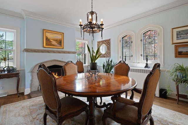 dining area featuring ornamental molding, an inviting chandelier, and hardwood / wood-style floors