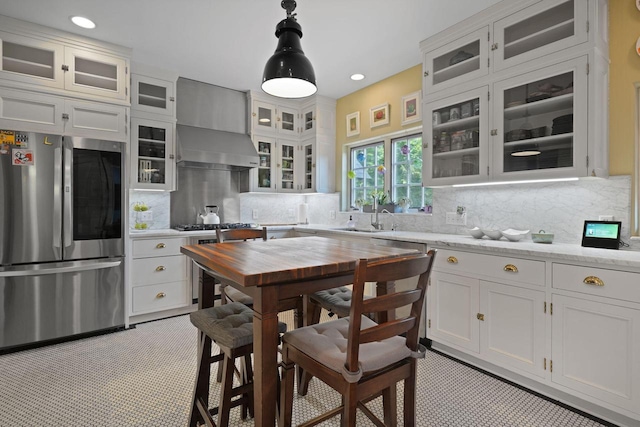 kitchen with white cabinets, stainless steel appliances, decorative backsplash, and decorative light fixtures