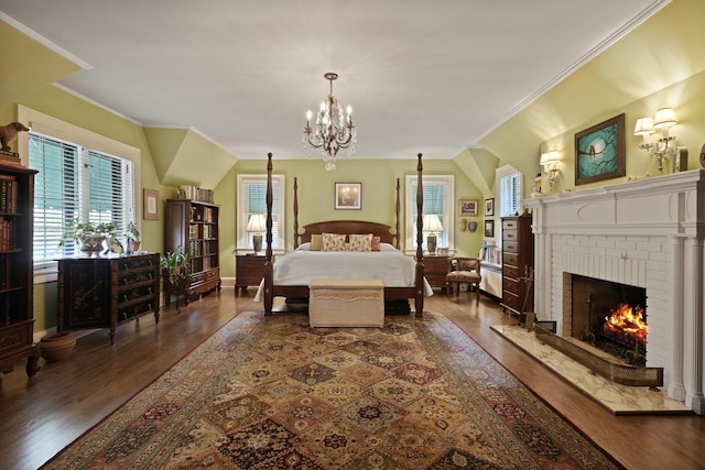 bedroom with a fireplace, ornamental molding, an inviting chandelier, and dark wood-type flooring