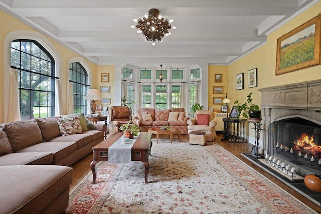 living room featuring wood-type flooring, ornamental molding, an inviting chandelier, and beamed ceiling