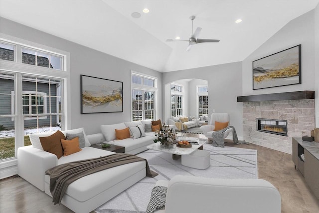 living room with a fireplace, light hardwood / wood-style floors, high vaulted ceiling, and ceiling fan