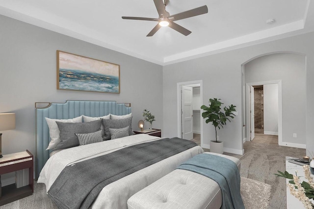 bedroom with a raised ceiling, ceiling fan, and light colored carpet