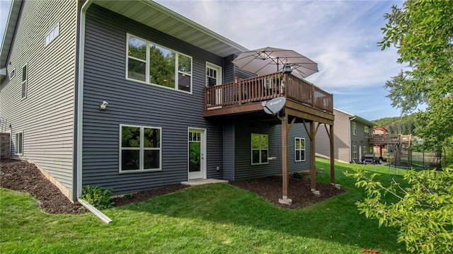 rear view of house featuring a lawn and a wooden deck