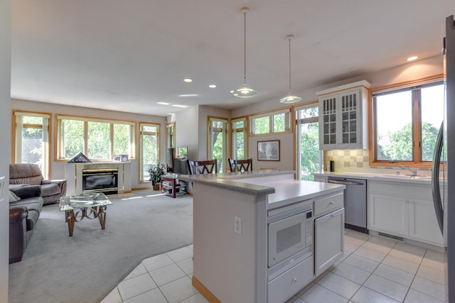 kitchen featuring a wealth of natural light, white microwave, dishwasher, and white cabinets