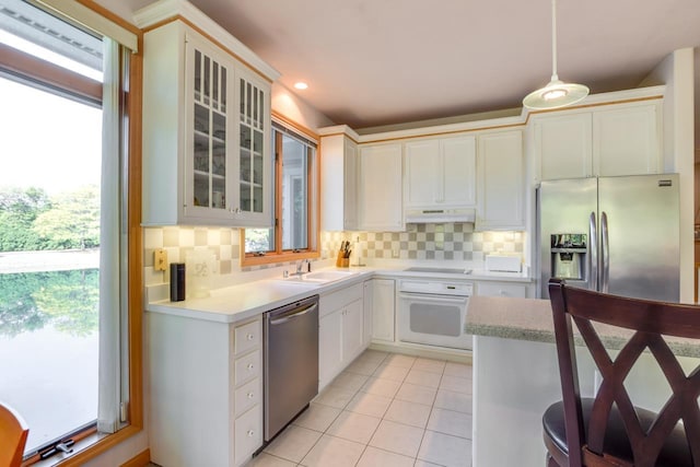 kitchen featuring appliances with stainless steel finishes, hanging light fixtures, a healthy amount of sunlight, and tasteful backsplash