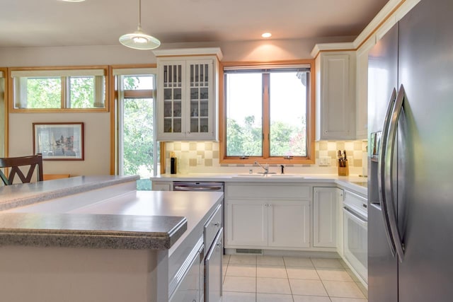 kitchen featuring pendant lighting, sink, tasteful backsplash, white cabinetry, and stainless steel refrigerator with ice dispenser