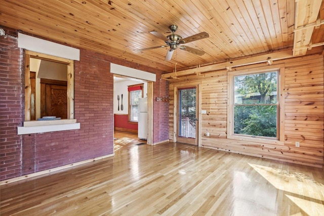 empty room featuring wood-type flooring, wood walls, ceiling fan, and wooden ceiling